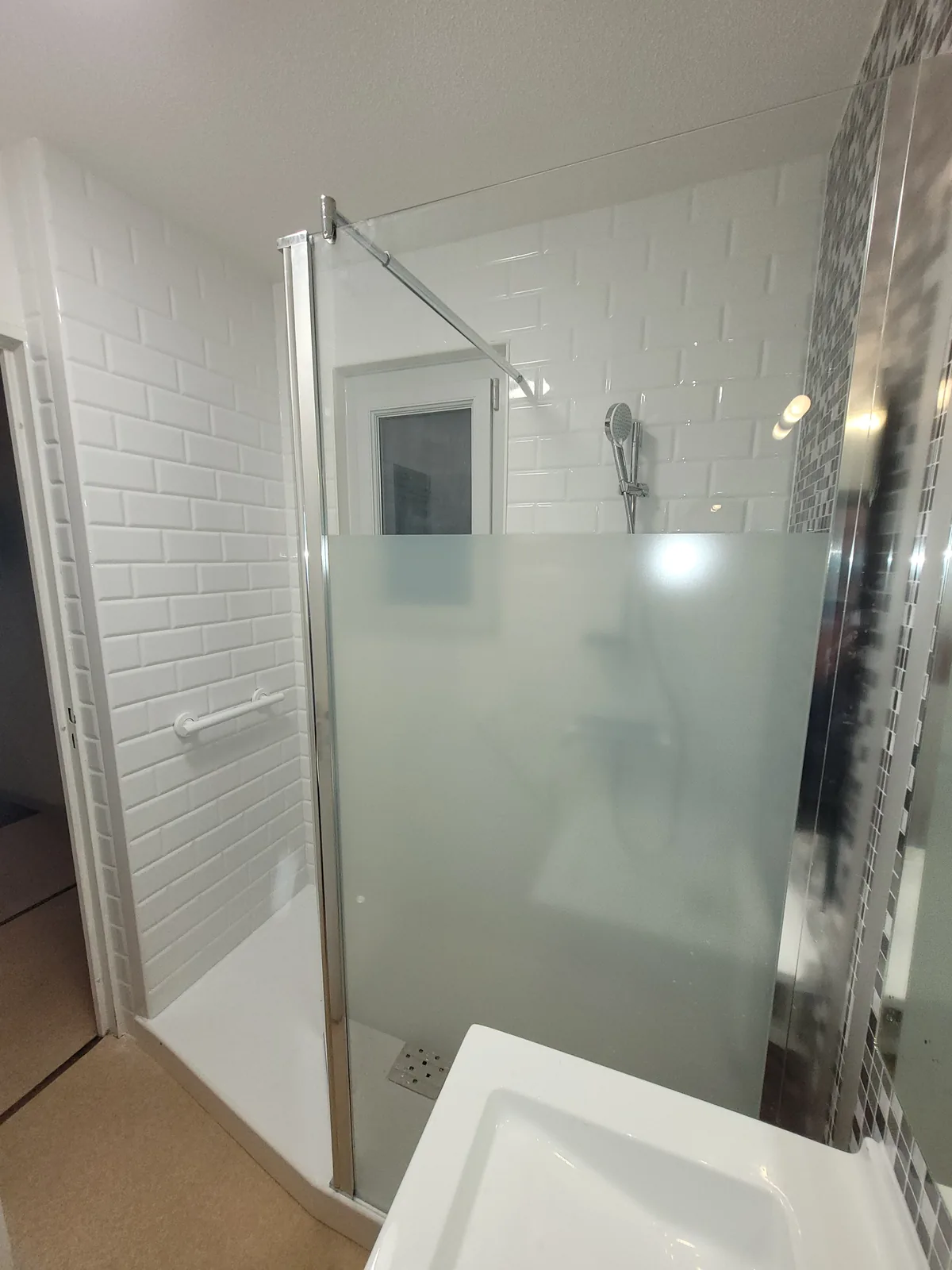 Douche terminée avec panneaux blancs et détail mosaïque