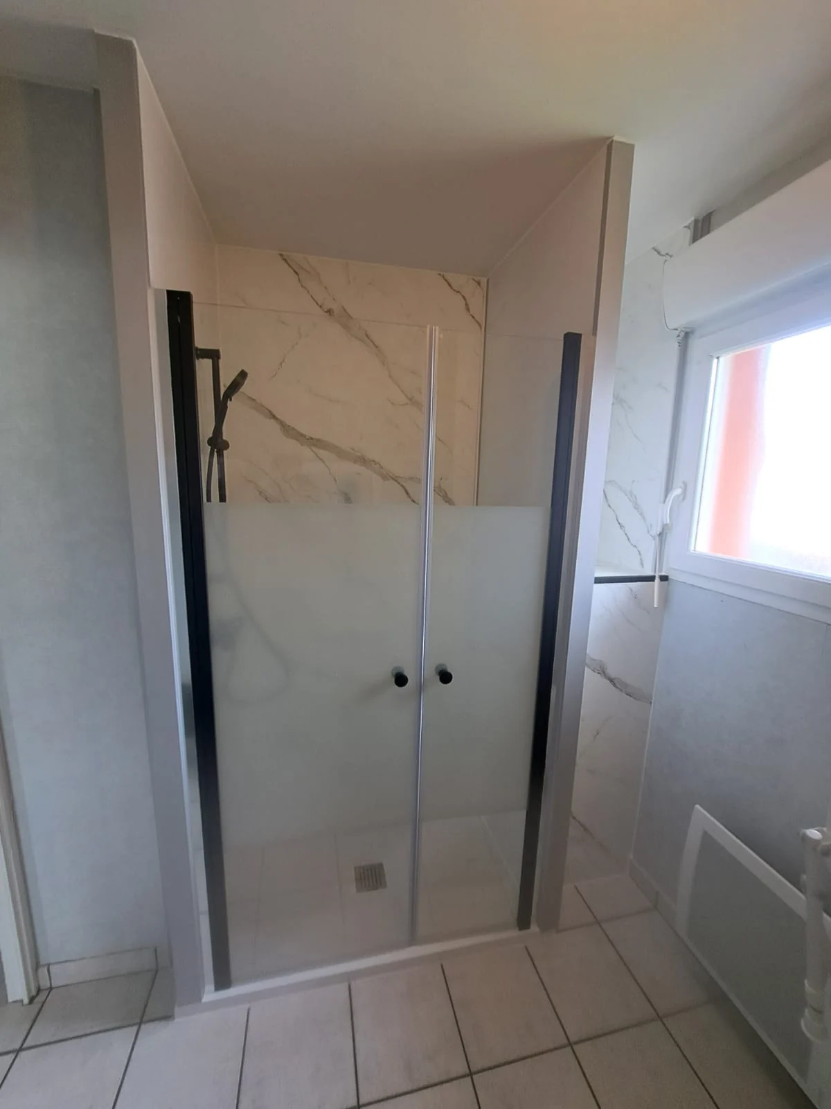 Douche terminée avec panneaux marbre clair et robinetterie noire