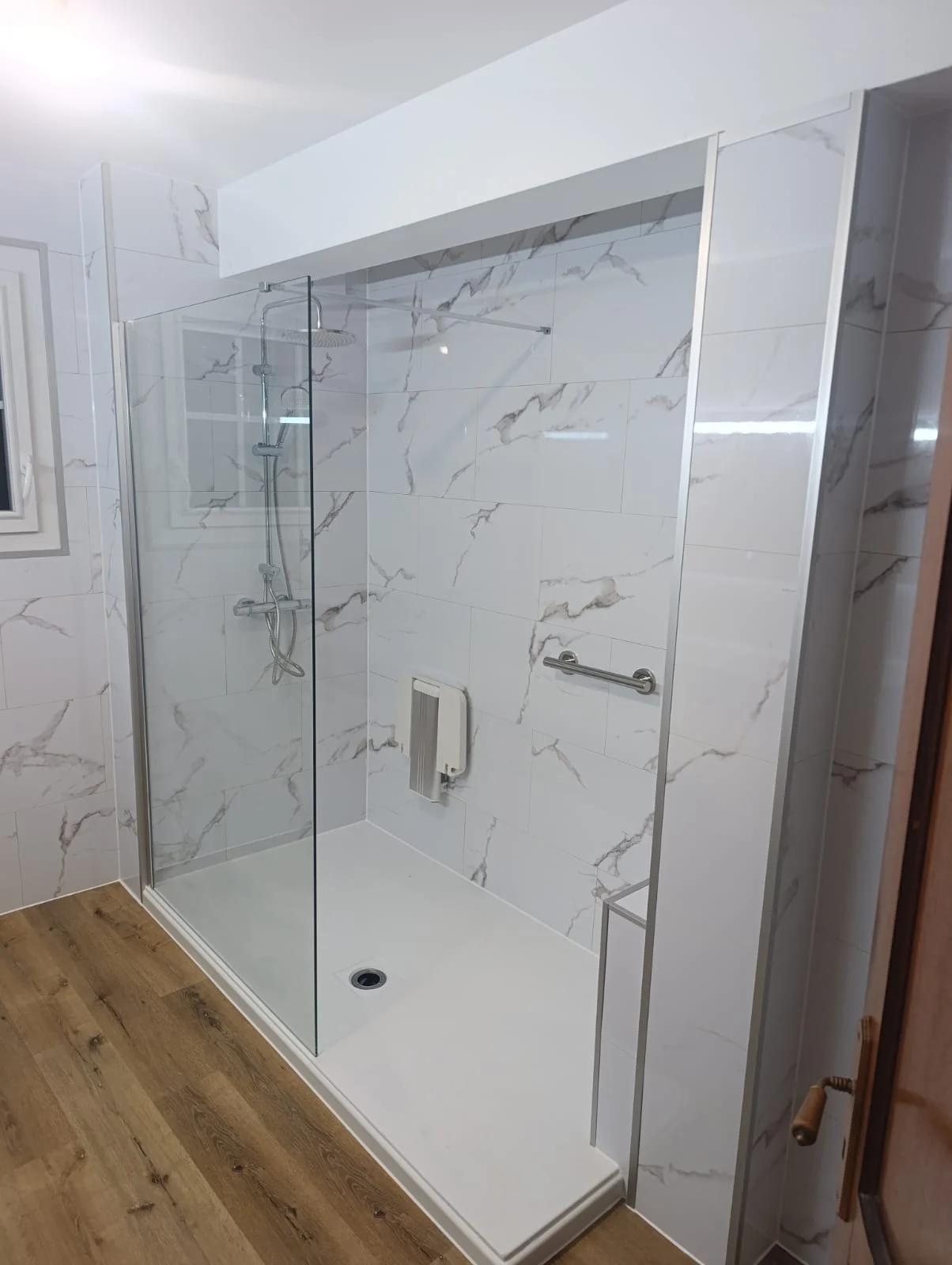 Grande douche sécurisée aux finitions marbre clair après rénovation