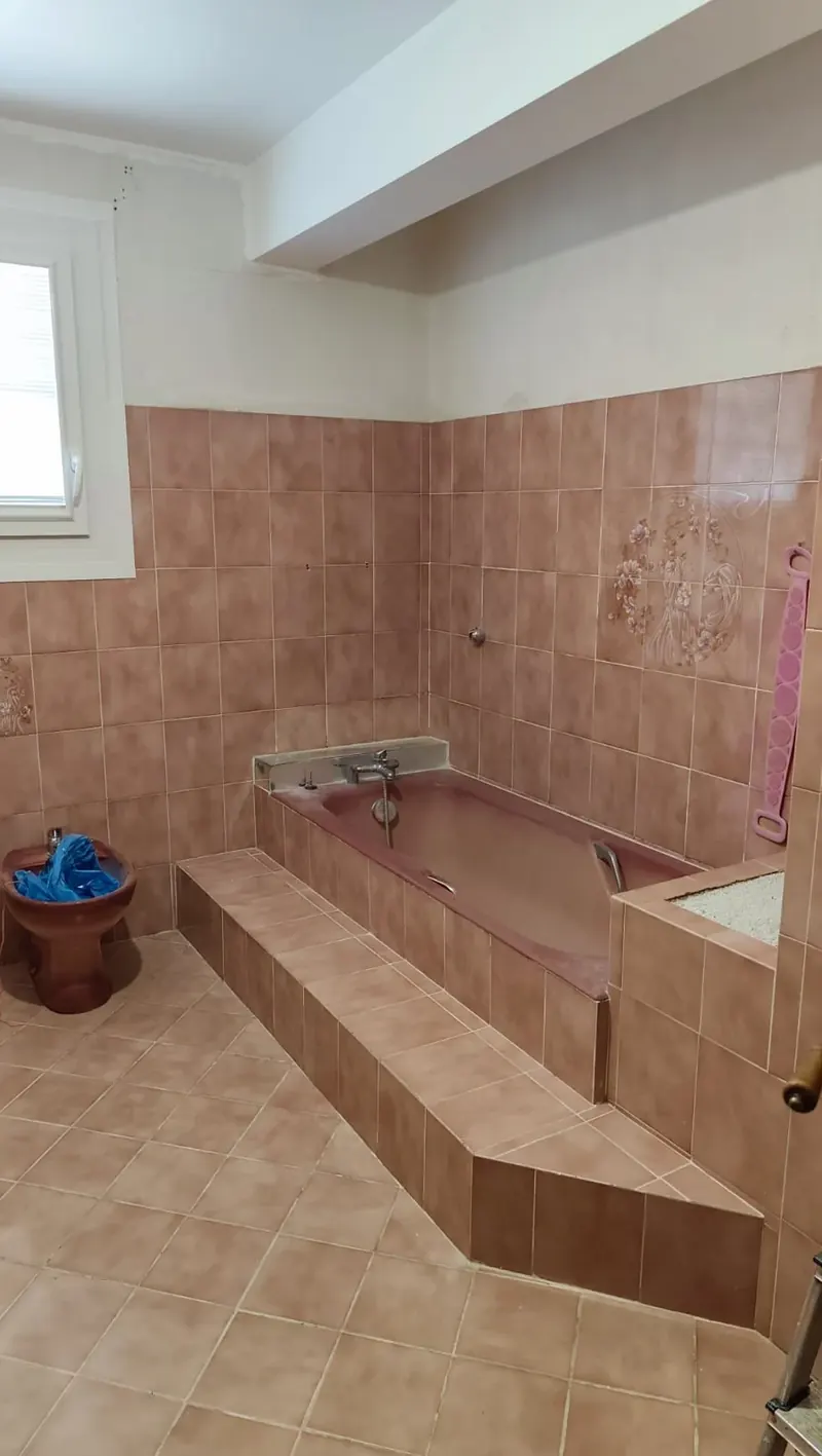 Salle de bain rose avec baignoire avant intervention